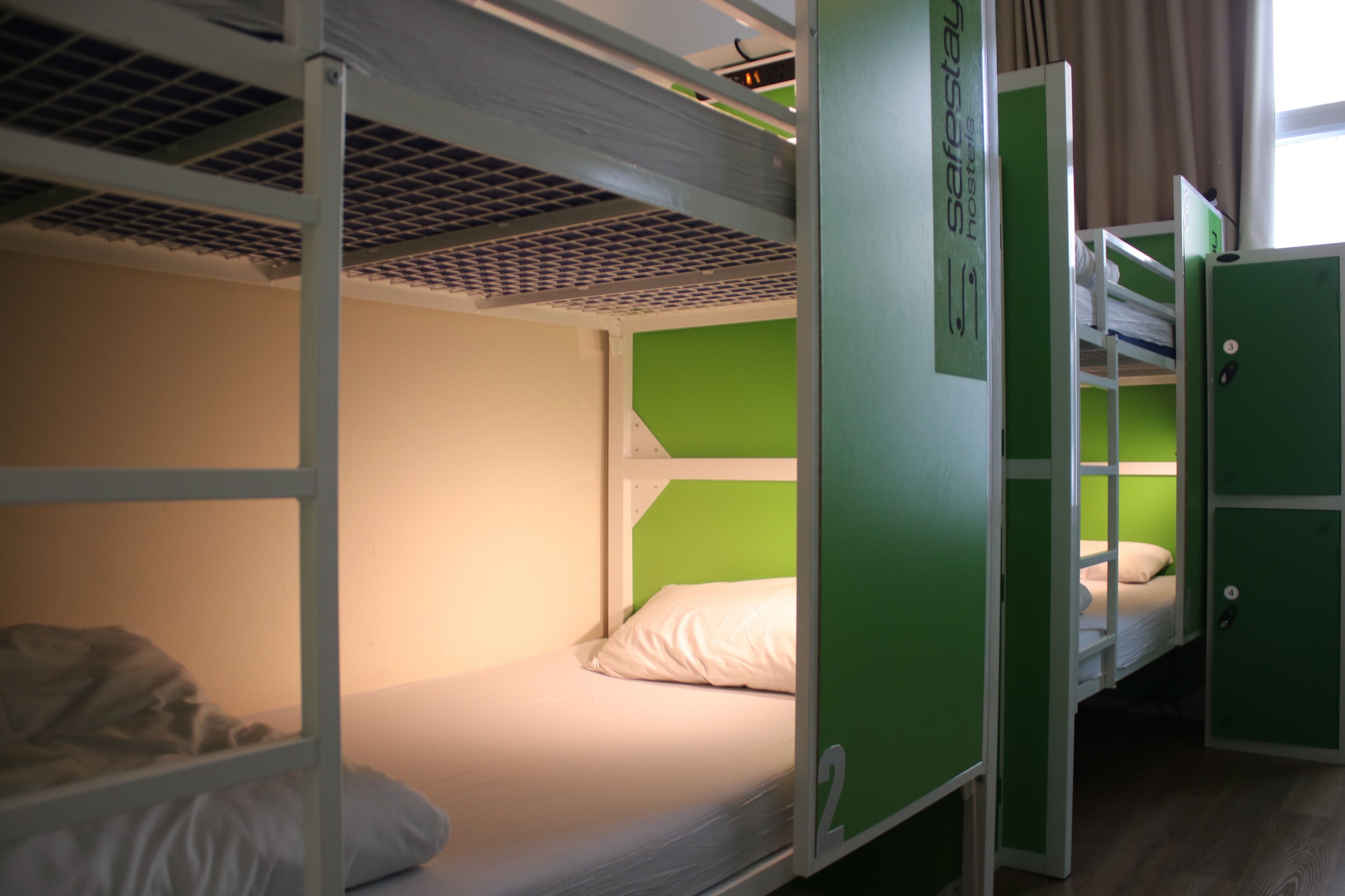 Une chambre avec un lit superposé, un mur d’accent vert, un matelas blanc et une structure de lit superposé en métal.