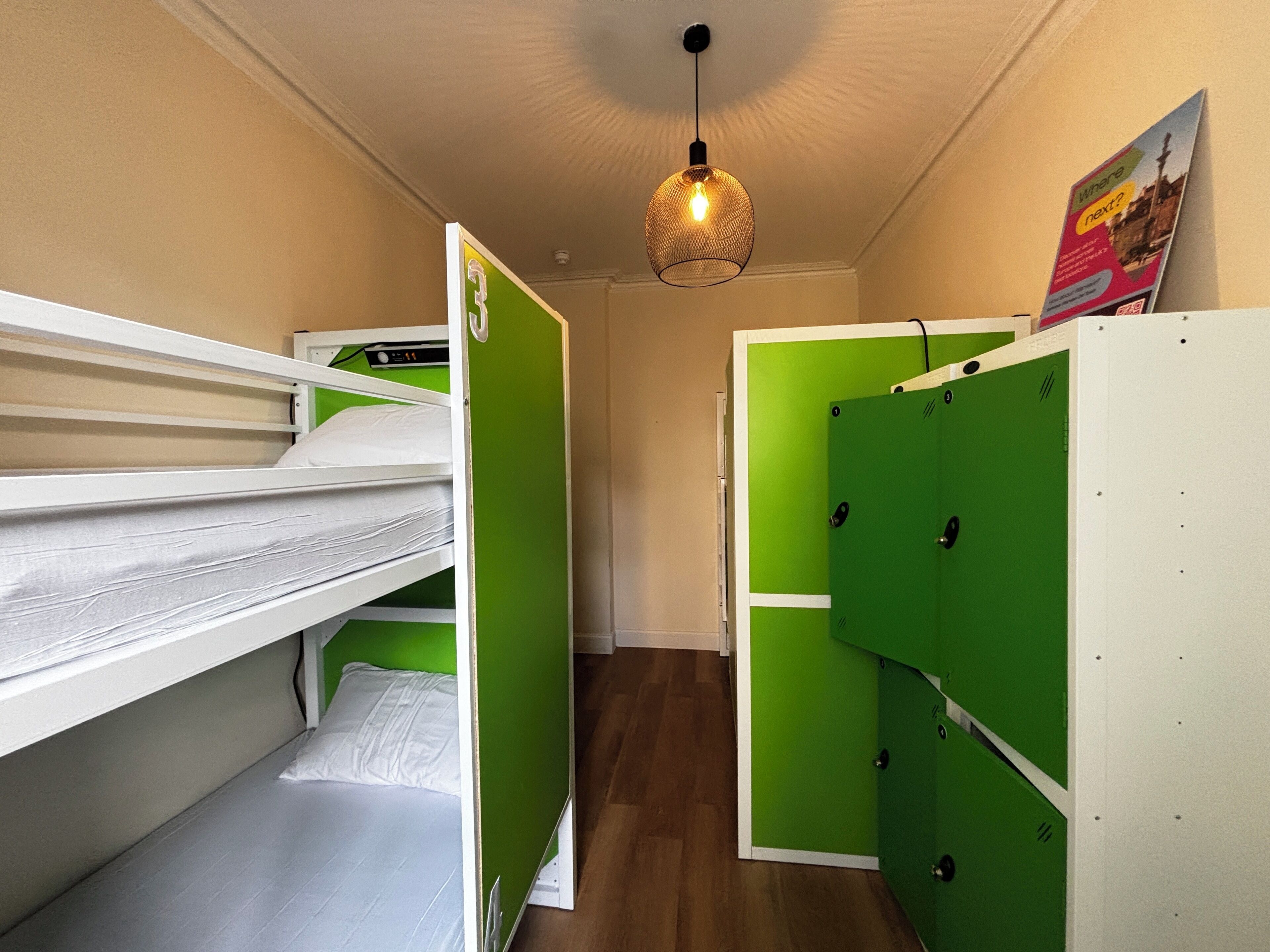 A compact room with bunk beds, a hanging light fixture, and a poster on the wall.