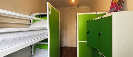 A compact room with bunk beds, a hanging light fixture, and a poster on the wall.
