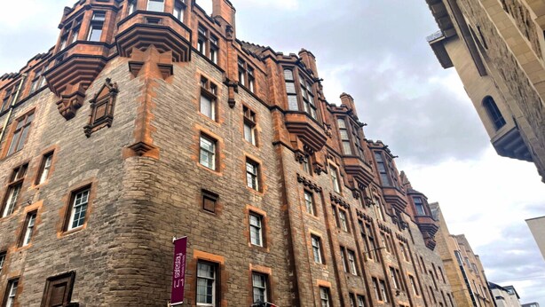 A historic building with a stone facade, multiple windows, and a prominent corner turret. - Safestay Edinburgh Cowgate (Edinburgh)
