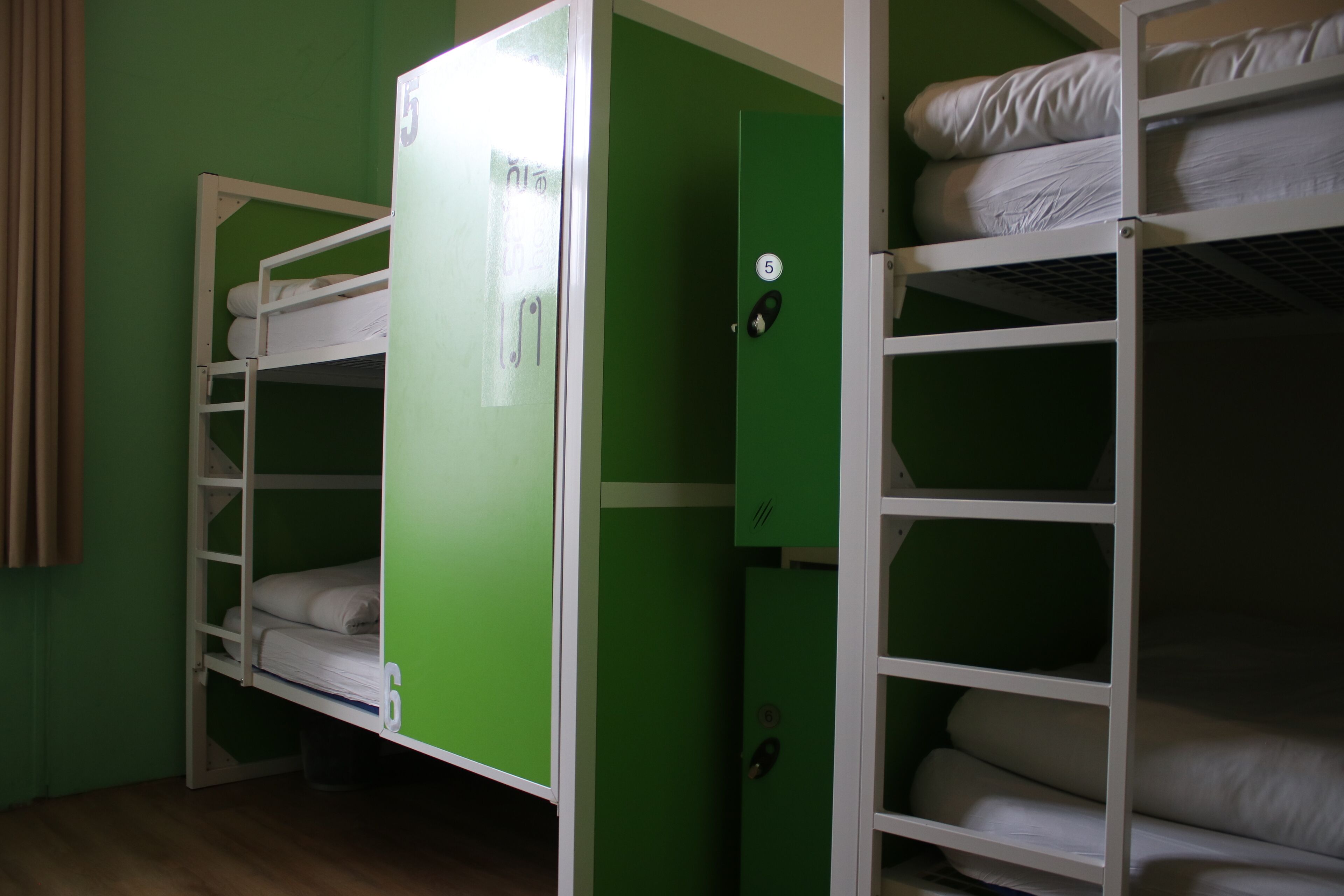 A bunk bed room with a green wardrobe and a white bed.