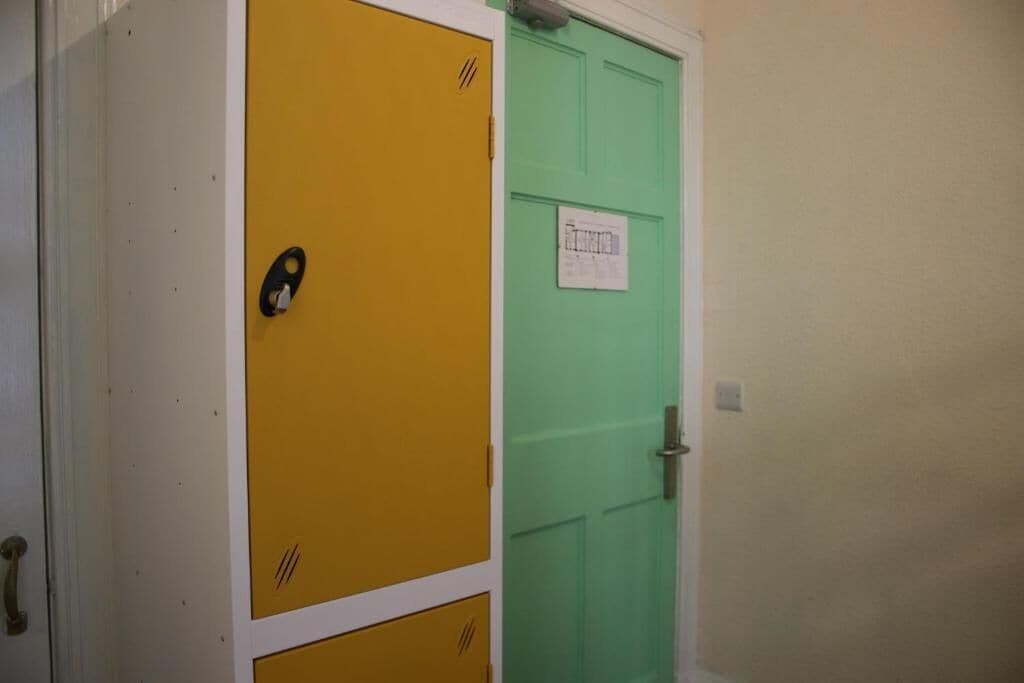 A hallway with a yellow and green door, a white wall, and a door handle.