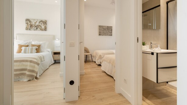 Una habitación de hotel moderna con una cama, una mesita de noche y un pequeño rincón de descanso.