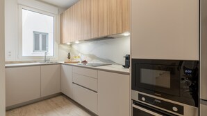 Una cocina moderna con armarios de madera, encimera de mármol, horno empotrado y microondas.