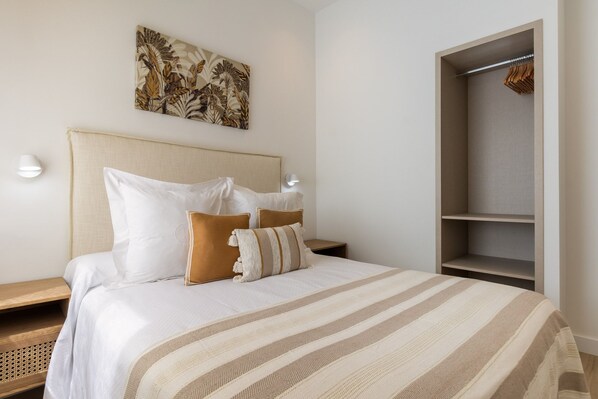 A neatly made bed with a striped bedspread, a headboard, and two bedside tables with lamps. - Cozy 2-Bed Apartment for 4 in Central Madrid (Madrid)