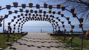 An outdoor pathway leading to a body of water, lined with potted plants on metal arches. - Welcome&Enjoy King Studio 1 (Ohrid)