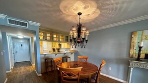 A dining area with a wooden table and chairs, a chandelier, and a kitchen in the background. - Gorgeous Gulf views from this 2bd/2 bath condo (Sarasota)