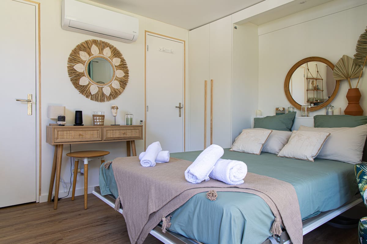 Un dormitorio con una cama, un escritorio, un espejo y un aire acondicionado instalado en la pared.