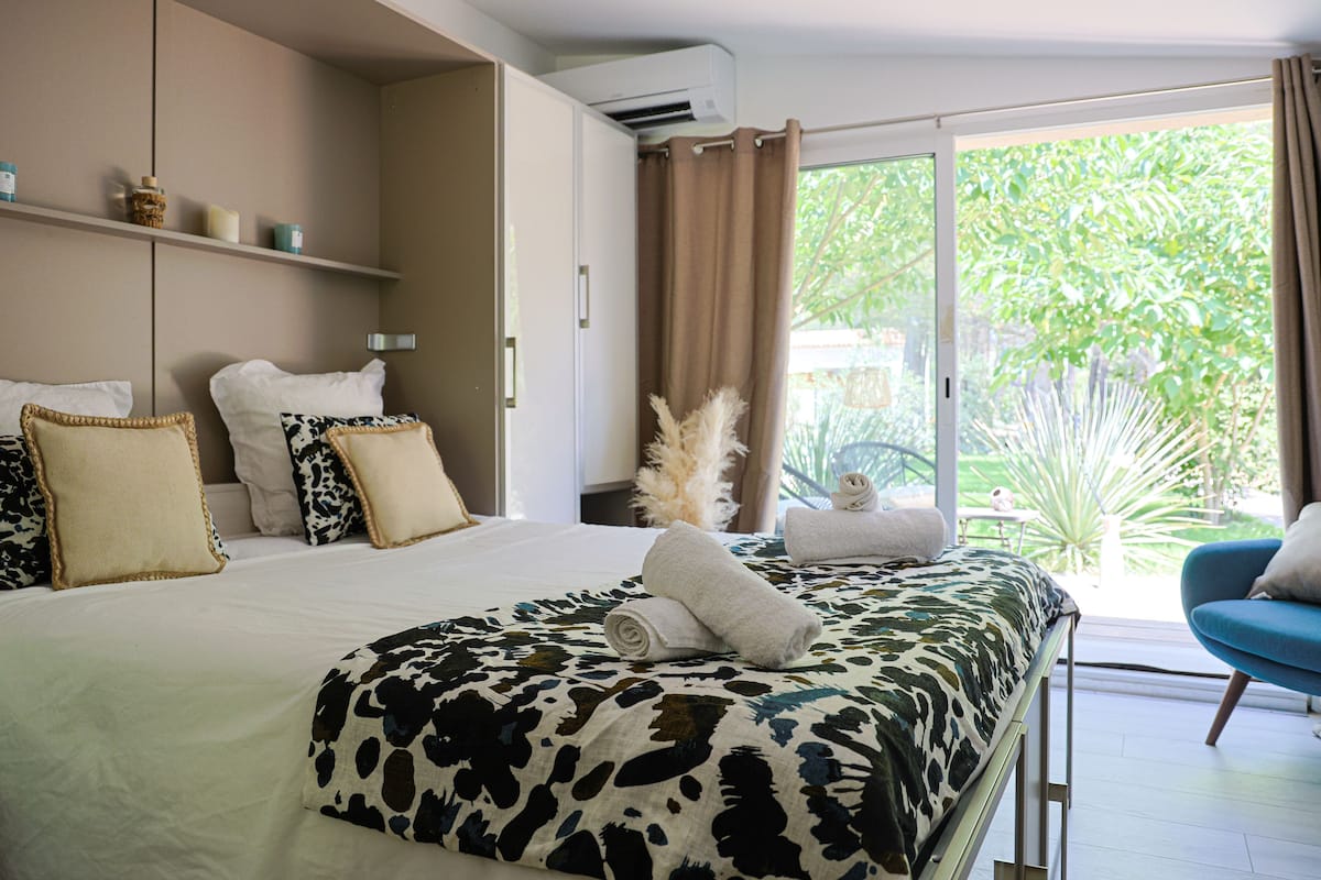 Un dormitorio con una cama, una silla azul y vistas a zonas verdes.