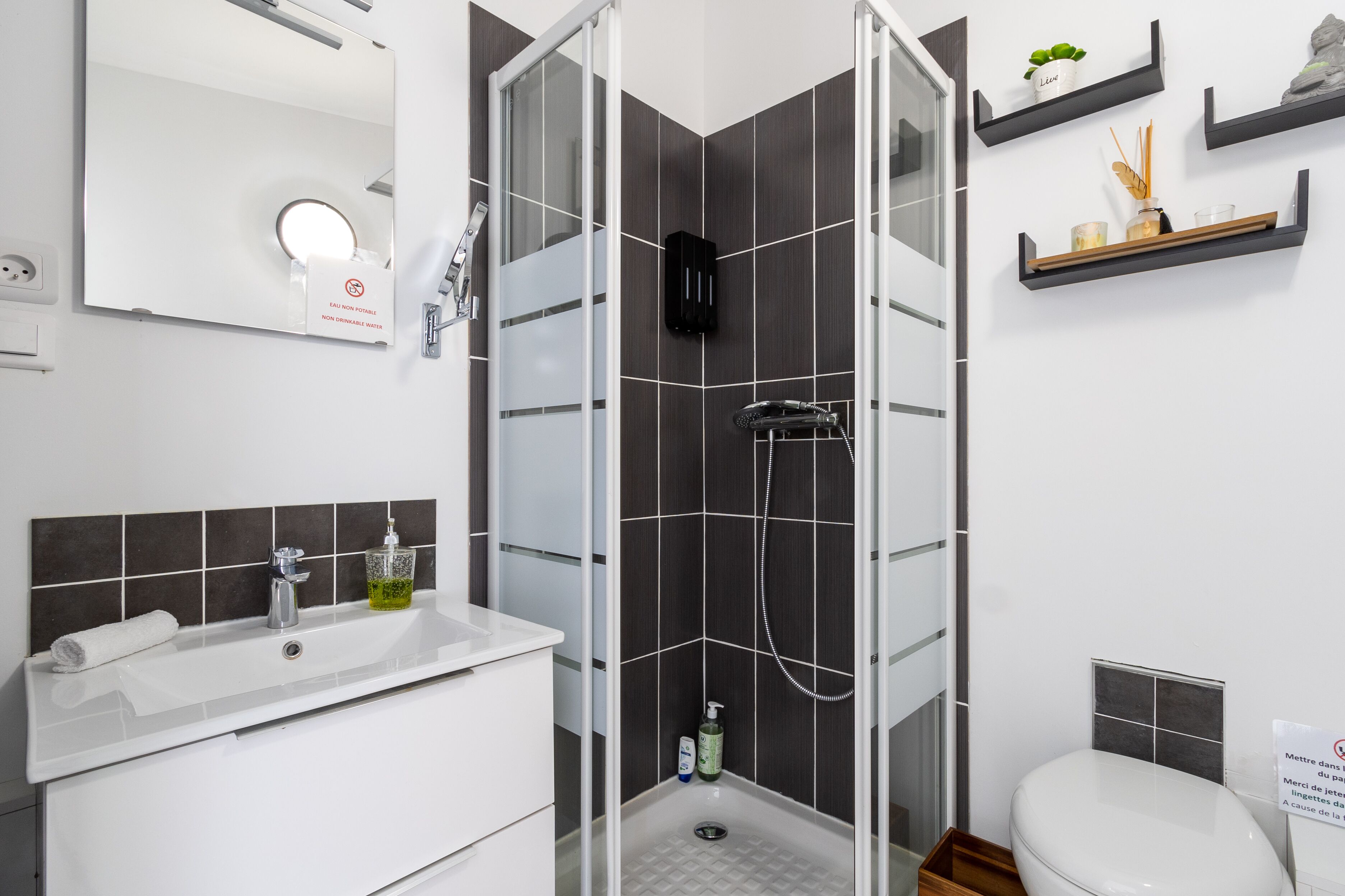 A modern bathroom with a glass-enclosed shower, a white sink with a mirror, and a toilet.