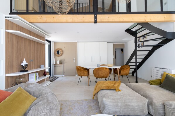 A modern living room with a sofa, a coffee table, and a dining area with chairs and a table.