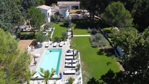 Eine Vogelperspektive auf ein Resort mit Schwimmbad, Liegestühlen und einem gepflegten Garten.
