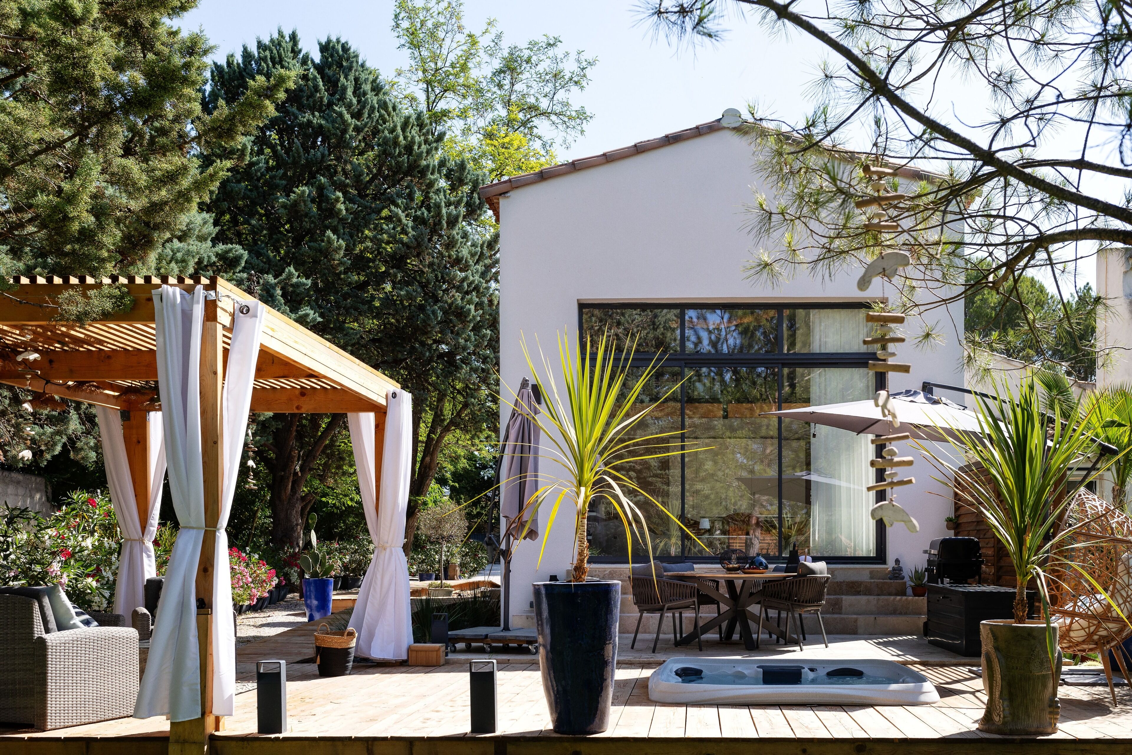 A modern outdoor patio with a pergola, seating, and a hot tub.