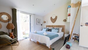 Ein Schlafzimmer mit einem Bett, einem Sofa, einem großen Fenster und Blick ins Freie.