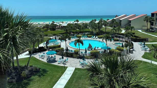 Un complexe hôtelier doté d’une piscine centrale, d’un espace de détente en plein air et offrant une vue sur la plage.