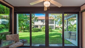 A room with a sliding glass door leading to a garden, a ceiling fan, and a dining table with a chair. - Bright and Peaceful garden view 2 Bed/ 2 Bath (Sarasota)
