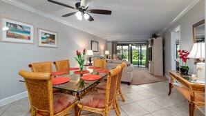 A dining area with a glass table, wicker chairs, and a ceiling fan. - Bright and Peaceful garden view 2 Bed/ 2 Bath (Sarasota)