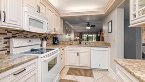 A kitchen with white cabinets, a microwave, stove, and a ceiling fan. - Bright and Peaceful garden view 2 Bed/ 2 Bath (Sarasota)