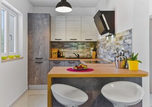 Una cucina moderna con isola centrale, mobili bianchi e una parete attrezzata dallo stile rustico.