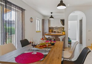 Un comedor con una mesa de madera, sillas y una cocina al fondo.