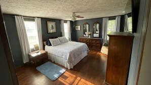 Un dormitorio con cama, cómoda y ventilador de techo.