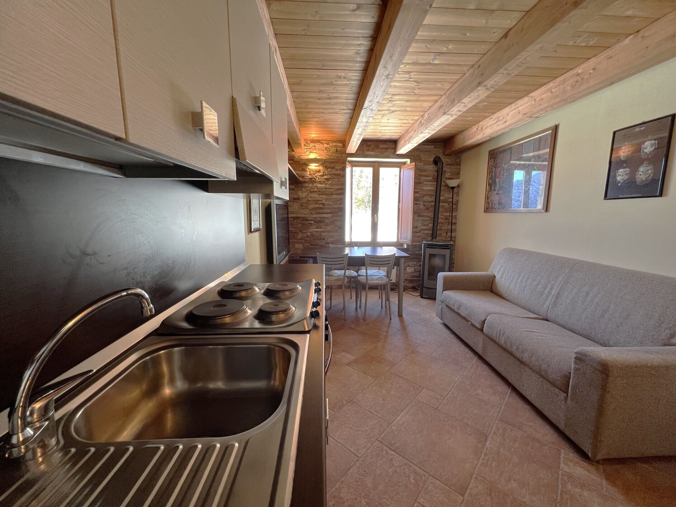 Una cocina moderna con electrodomésticos de acero inoxidable, un comedor con mesa y sillas, y una sala de estar con sofá.