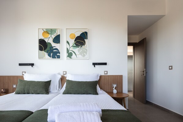 A hotel room with two beds, a wooden headboard, a nightstand, and two wall-mounted lamps.