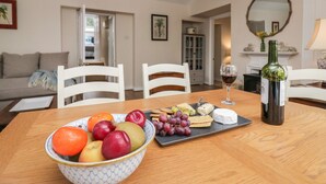 A dining table with a bowl of fruit, cheese, crackers, and a wine bottle. - Summerhow Retreat (Kendal)