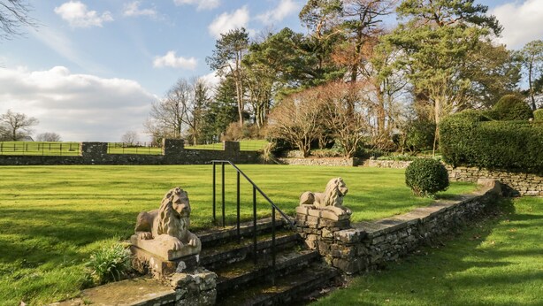 A stone bridge with lion statues, a stone wall, and a grassy field with trees in the background. - Summerhow Retreat (Kendal)