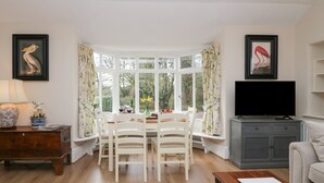 A dining area with a bay window, a television, and a sofa. - Summerhow Retreat (Kendal)