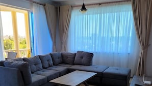 A modern living room with a sectional sofa, a wooden coffee table, and a small table. - Lux Suites Micasa Royal Apartments Nyali (Mombasa)