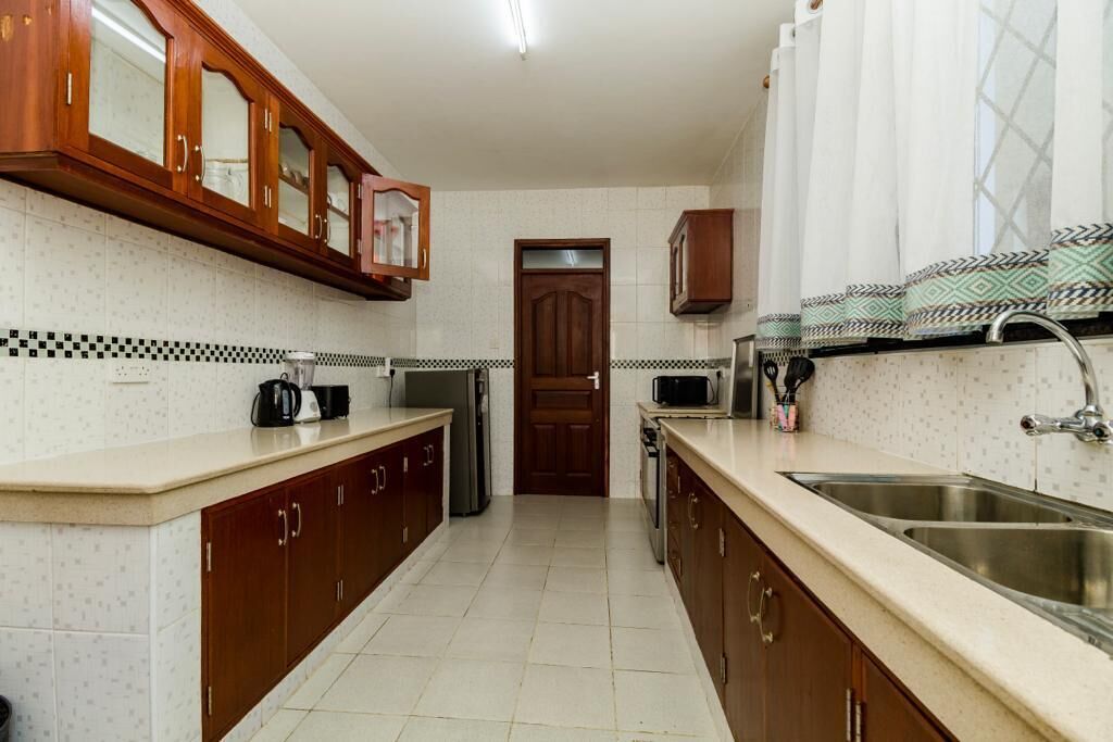 A kitchen with wooden cabinets, a microwave, a coffee maker, and a sink.
