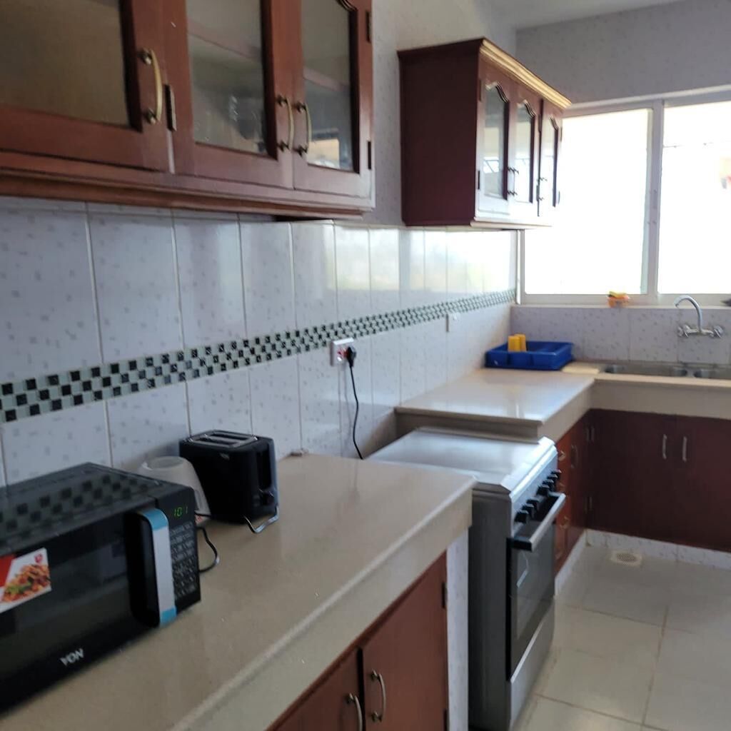A kitchen with a microwave, toaster, and oven. There is a window with a view of the outside.