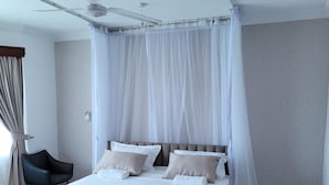 A modern bedroom with a large bed, a ceiling fan, and sheer curtains. - Lux Suites Micasa Royal Apartments Nyali (Mombasa)