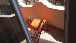 Un balcon avec une chaise en métal et une petite table.
