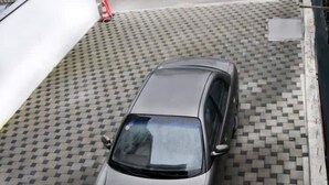 Une voiture est garée dans un parking couvert dont le sol est recouvert d’un motif à carreaux.
