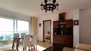 Una sala de estar con una araña, un comedor con una mesa y sillas, y una estantería.
