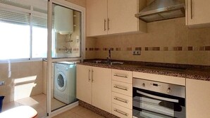 Cocina compacta con lavadora, horno y un pequeño comedor.