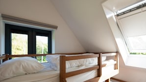 Habitación tipo dormitorio con literas, un tragaluz y una ventana con persianas.