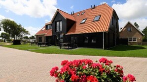 Ein zweigeschossiges Haus mit rotem Ziegeldach, schwarzem Anstrich und einem gepflasterten Auffahrt.