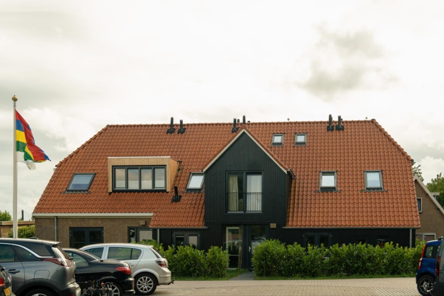 A two-story house with a red-tiled roof, a small attached garage, and a flagpole with a flag.