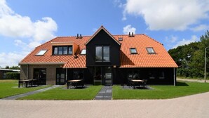 Ein zweistöckiges Haus mit rotem Ziegeldach, einem zentralen Eingang und einem gepflasterten Auffahrt.