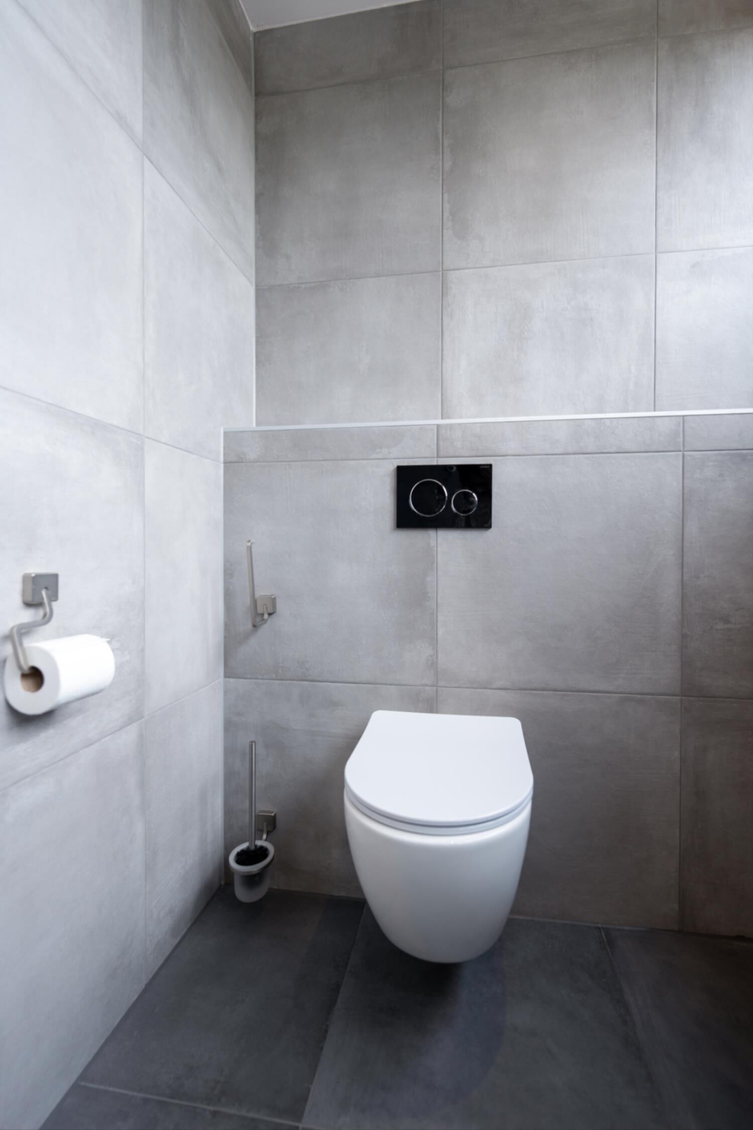 A modern bathroom with a toilet, a toilet paper holder, and a bidet.