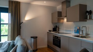 Eine moderne Küche mit eingebautem Backofen, Spüle und einer Edelstahl-Mülltonne.