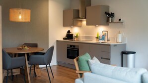 Una cocina moderna con comedor, que incluye una mesa de madera, sillas grises y un sofá gris.