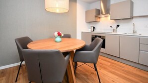 Una cocina moderna con armarios grises, una mesa de comedor de madera con cuatro sillas y una lámpara colgante.