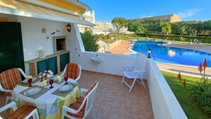 Eine Terrasse mit Esstisch für zwei Personen, einem Pool und Blick auf die Umgebung.
