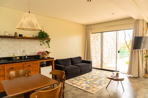 A modern kitchen with a dining area, a sofa, and a TV.