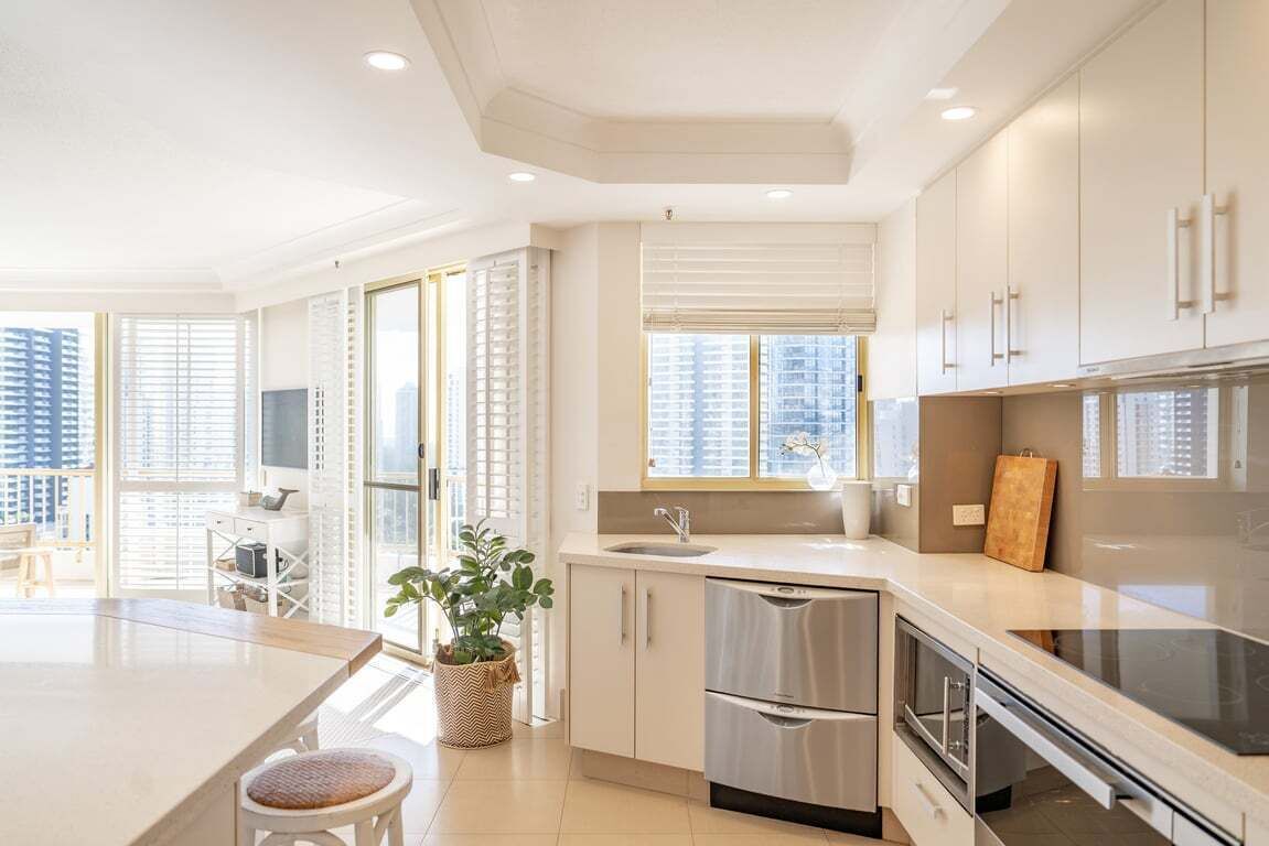 A modern kitchen with a central island, stainless steel appliances, and a view of high-rise buildings.