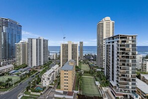 Un immeuble résidentiel de grande hauteur doté de nombreux balcons, d’un court de tennis et offrant une vue sur l’océan.